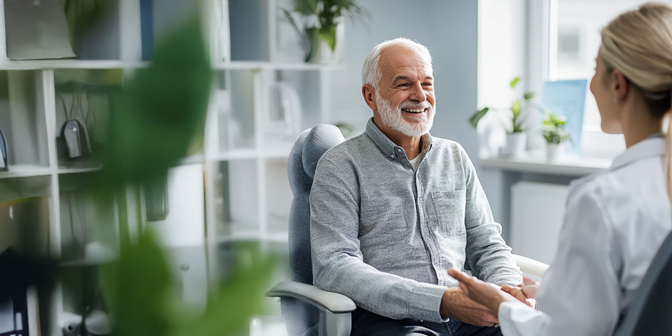 Older man speaking with smiling nurse in a modern medical office, confident Medicare client of Cephas Insurance Solutions